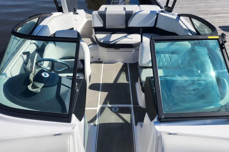 Slide: The Image of 2023 Regal 21 OBX boat interior with seating and steering wheel, docked by the water. - 10