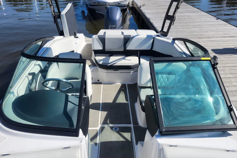 Slide: The Image of 2023 Regal 21 OBX boat interior with seating and steering wheel, docked by water. - 12