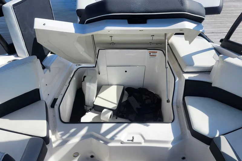 Slide: The Image of 2023 Regal 21 OBX boat interior storage compartment with open hatch and seating. - 23