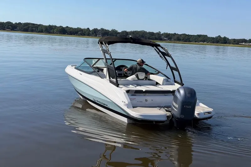 Slide: The Image of 2023 Regal 21 OBX boat cruising on a calm lake with a Yamaha outboard motor. - 3