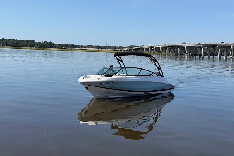 Slide: The Image of 2023 Regal 21 OBX boat on calm water near a bridge, under clear blue sky. - 31