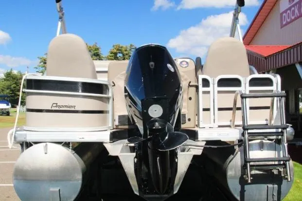 Slide: The Image of 2012 Premier 221 Gemini pontoon boat with outboard motor and ladder, docked under blue sky. - 5
