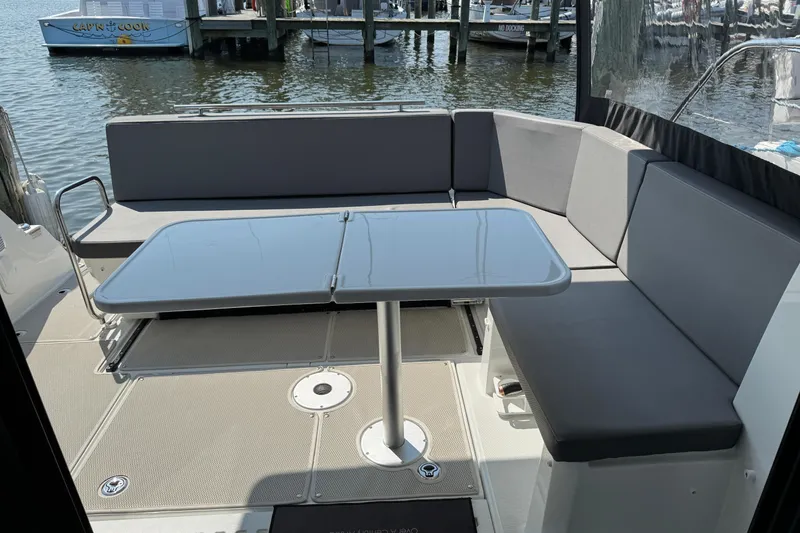 Slide: The Image of 2024 Beneteau Antares 11 boat interior with seating and table, docked by the water. - 18