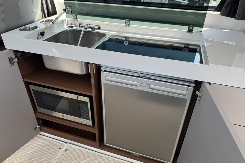 Slide: The Image of 2024 Beneteau Antares 11 kitchen with sink, stove, microwave, and fridge. - 21