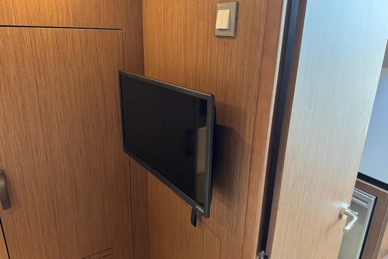 Slide: The Image of Wall-mounted TV in 2024 Beneteau Antares 11 boat interior with wooden paneling. - 25