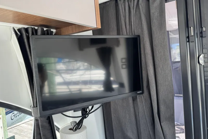 Slide: The Image of Flat-screen TV inside 2024 Beneteau Antares 11 boat, surrounded by dark curtains. - 26