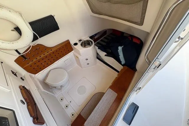 Slide: The Image of 2013 Grady-White Canyon 336 cabin interior with toilet, sink, and seating area. - 17