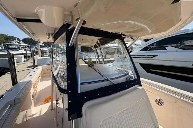 Slide: The Image of 2013 Grady-White Canyon 336 boat interior, featuring seating and helm area at a marina. - 23