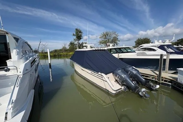 Slide: The Image of 2013 Grady-White Canyon 336 boat docked with cover, twin outboard engines, clear sky. - 4