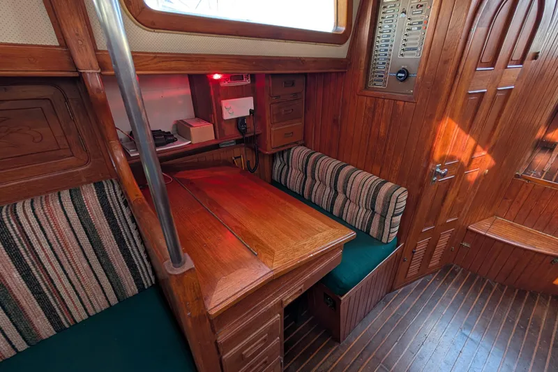 Slide: The Image of Cozy wooden interior of 1983 Robert Perry 41 sailboat with striped seating and navigation area. - 14
