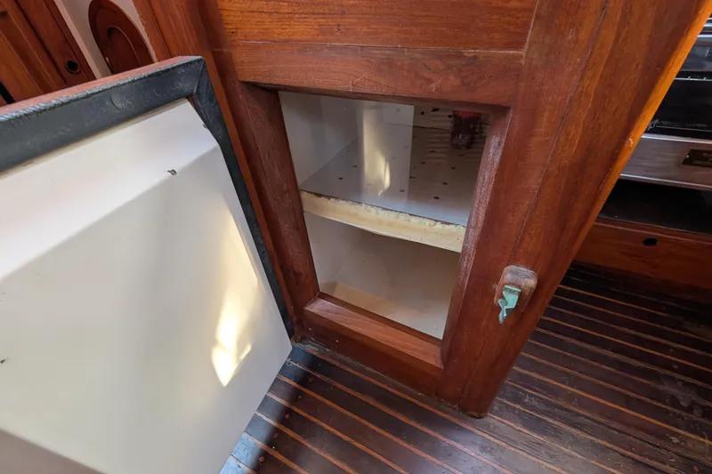 Slide: The Image of Wooden cabinet interior on a 1983 Robert Perry 41 boat, open door, empty shelves. - 19