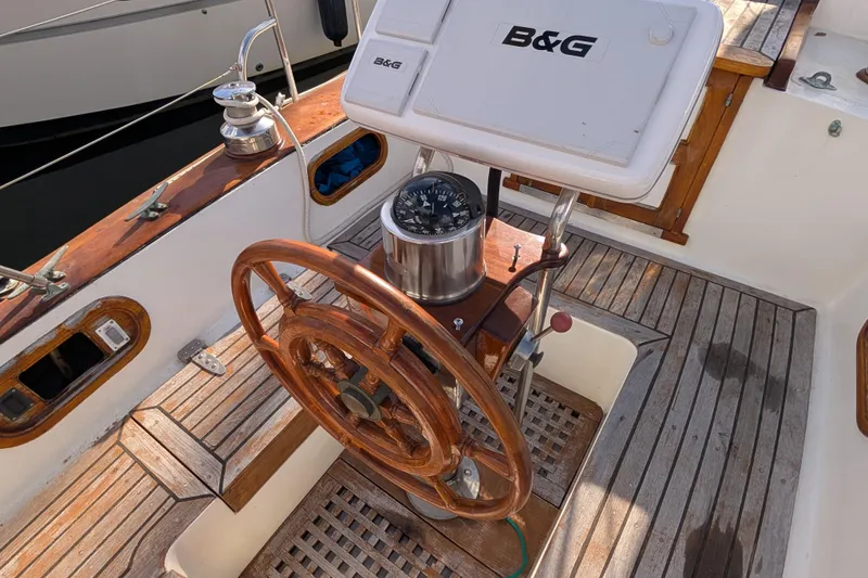 Slide: The Image of Wooden steering wheel and compass on a 1983 Robert Perry 41 sailboat deck. - 32