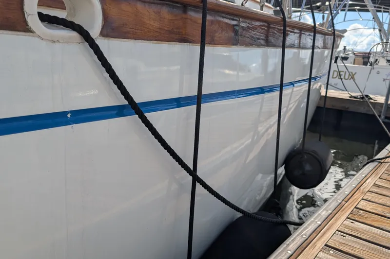 Slide: The Image of Side view of a 1983 Robert Perry 41 yacht docked with fenders and ropes. - 45