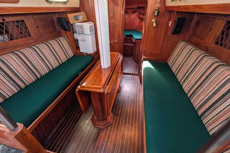 Slide: The Image of Interior of 1983 Robert Perry 41 sailboat with wooden furnishings and green cushions. - 5