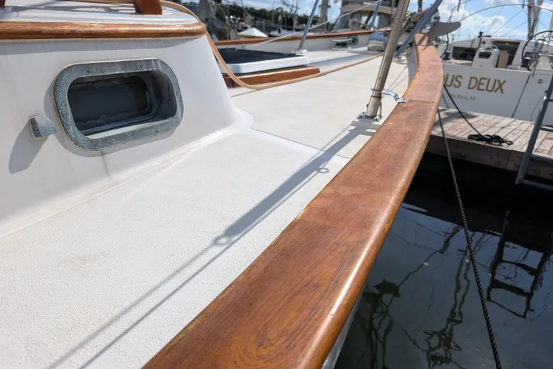 Slide: The Image of 1983 Robert Perry 41 sailboat deck with wooden trim and porthole, docked at marina. - 50