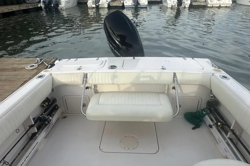 Slide: The Image of 2004 Grady-White Tournament 225 boat interior with seating and fishing rods at dock. - 18