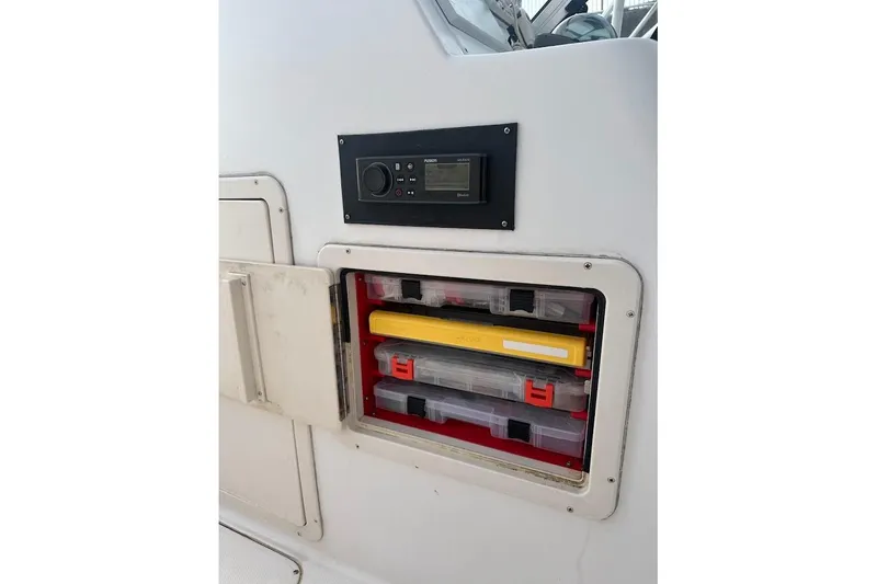 Slide: The Image of 2004 Grady-White Tournament 225 boat storage compartment with organized tackle boxes and control panel. - 23