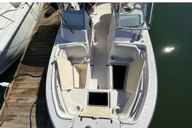 Slide: The Image of 2004 Grady-White Tournament 225 boat docked, open storage compartments, white seating, sunny day. - 8