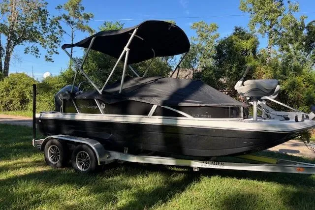 Slide: The Image of 2025 Hurricane FunDeck 198 RE OB boat on trailer, covered and parked on grass. - 2