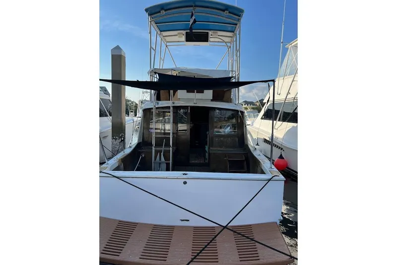 Slide: The Image of 1963 Hatteras 34 Convertible boat docked, rear view with canopy and ladder. - 11