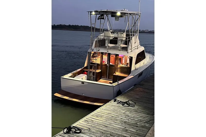 Slide: The Image of 1963 Hatteras 34 Convertible yacht docked at sunset, illuminated interior. - 14