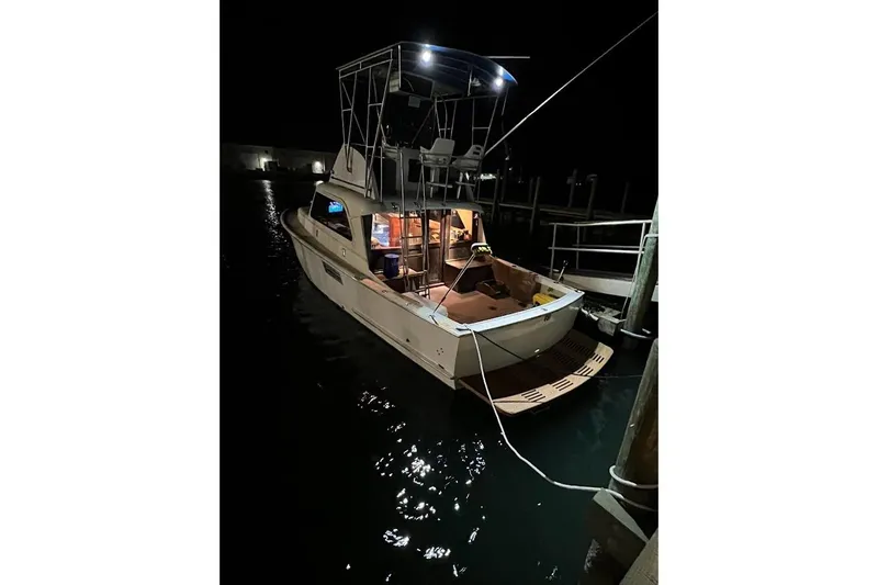 Slide: The Image of 1963 Hatteras 34 Convertible boat docked at night, illuminated by onboard lights. - 17