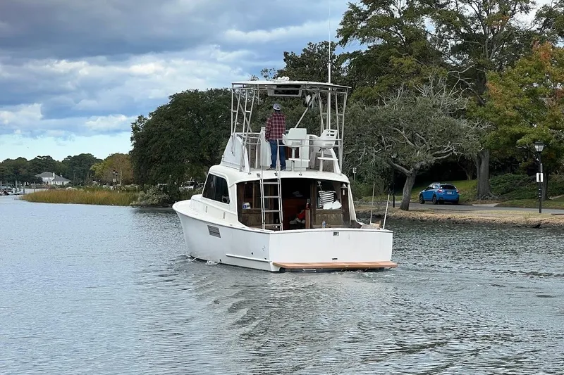 Slide: The Image of 1963 Hatteras 34 Convertible boat cruising on a scenic waterway with trees and cloudy sky. - 25