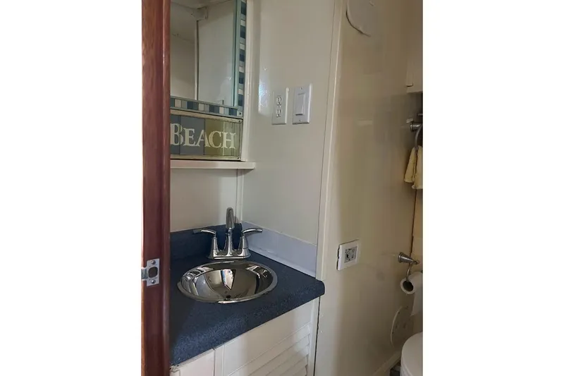 Slide: The Image of 1963 Hatteras 34 Convertible bathroom with sink, mirror, and beach-themed decor. - 29