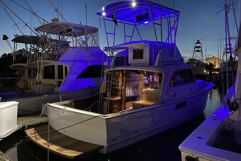 Slide: The Image of 1963 Hatteras 34 Convertible yacht illuminated at night in a marina. - 9