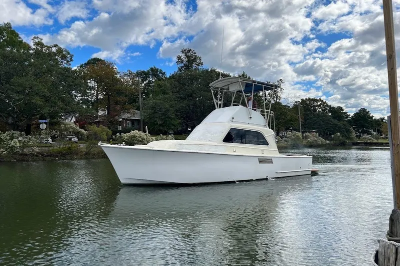 The Image of 1963 Hatteras 34 Convertible boat on a calm river under a partly cloudy sky. - 1