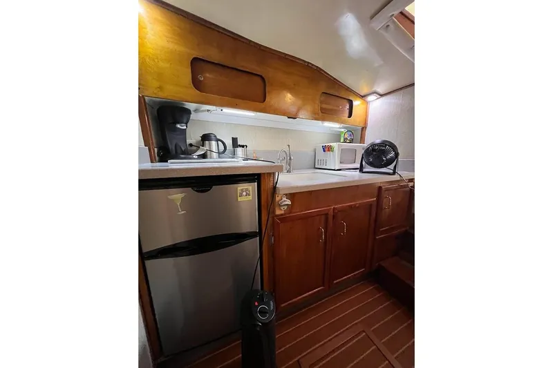 Slide: The Image of 1963 Hatteras 34 Convertible yacht kitchen with wooden cabinets, mini fridge, and appliances. - 32