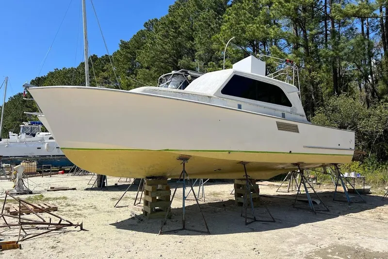 Slide: The Image of 1963 Hatteras 34 Convertible boat on stands, surrounded by trees. - 6