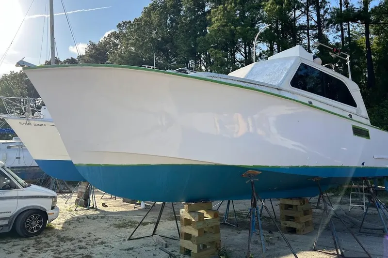 Slide: The Image of 1963 Hatteras 34 Convertible boat on stands, surrounded by trees and vehicles. - 7