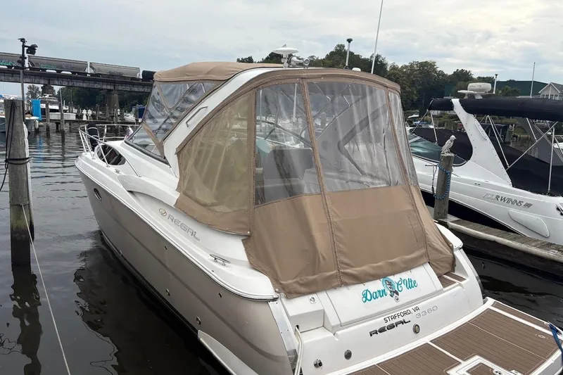 The Image of 2010 Regal 3360 Window Express boat docked at marina with tan canopy. - 1