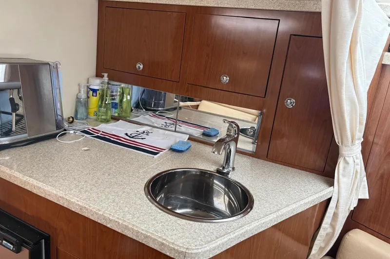 Slide: The Image of 2010 Regal 3360 Window Express yacht kitchenette with sink, espresso machine, and storage cabinets. - 10