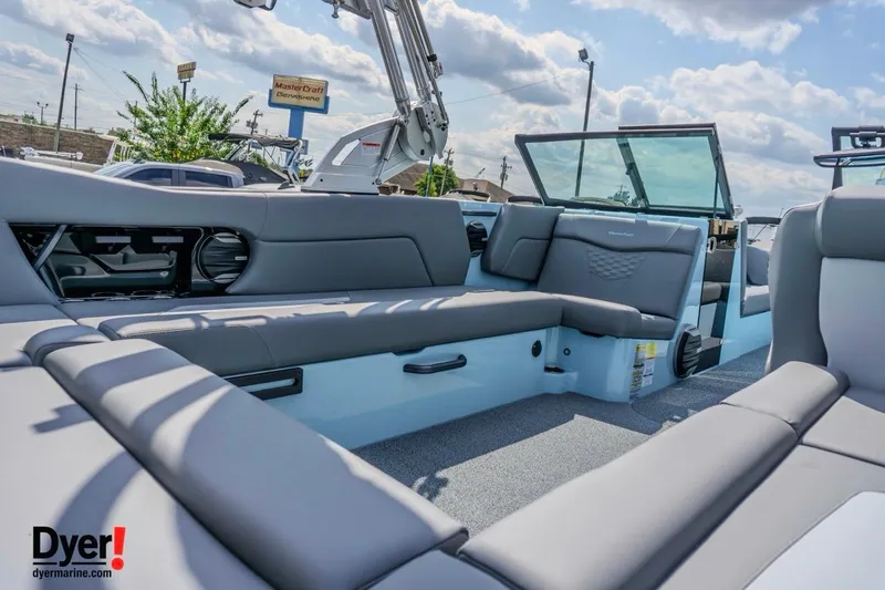Slide: The Image of 2026 MasterCraft NXT24 boat interior with gray seating, open deck, and clear skies. - 8