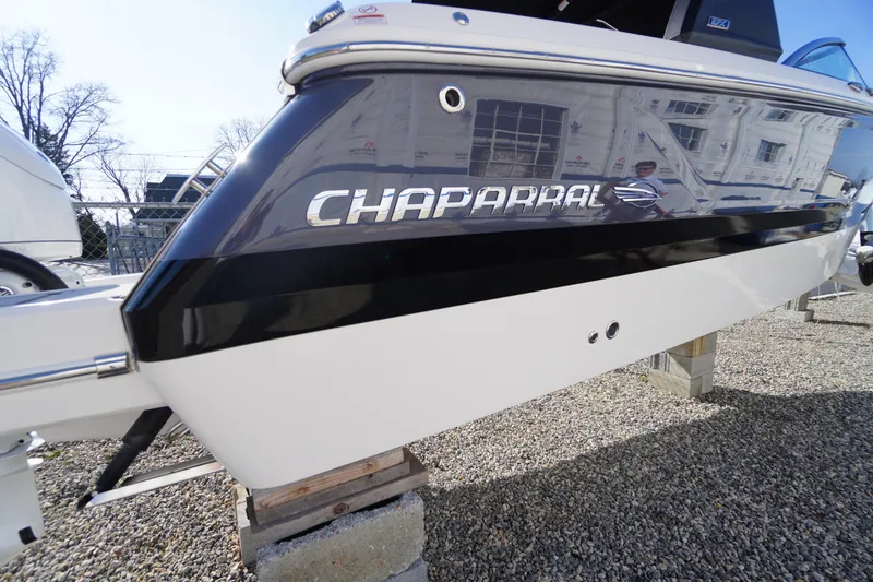Slide: The Image of 2026 Chaparral 250 OSX boat side view with logo, displayed outdoors. - 2