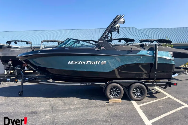 The Image of 2026 MasterCraft XT22 T boat on trailer, parked outdoors, under clear blue sky. - 0