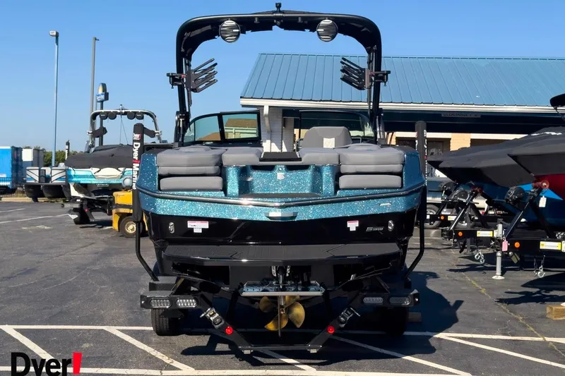 Slide: The Image of 2026 MasterCraft XT22 T boat with blue accents, parked outdoors. - 2