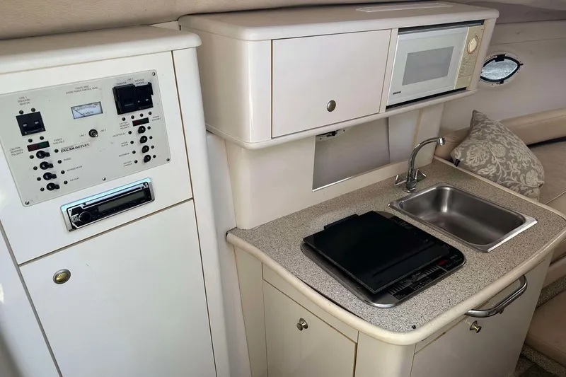 Slide: The Image of 2000 Maxum 2700 SCR boat interior with kitchenette, sink, microwave, and control panel. - 13