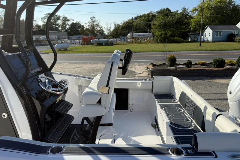 Slide: The Image of 2023 Tidewater 232 SS boat interior with steering console and seating, parked outdoors. - 13