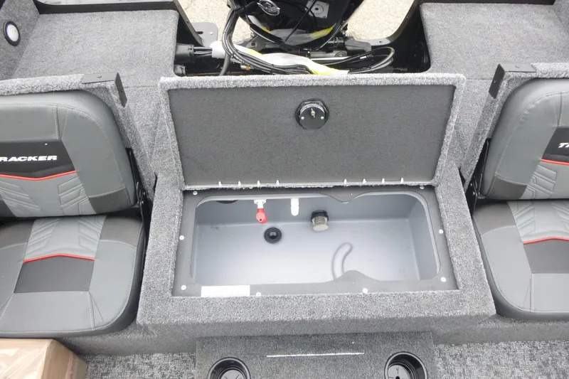 Slide: The Image of 2026 Tracker Targa V-19 Combo boat storage compartment with equipment and carpeted interior. - 13