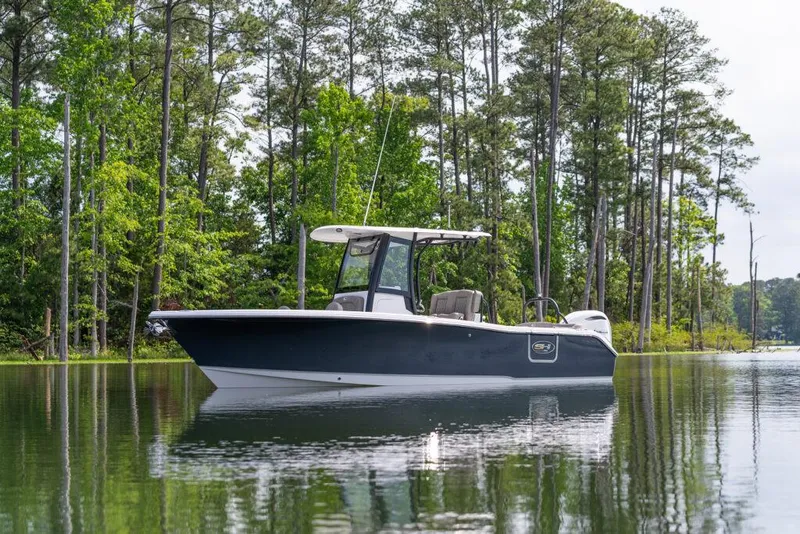 The Image of 2026 Sea Hunt Ultra 255 SE boat on calm lake with forest backdrop. - 1