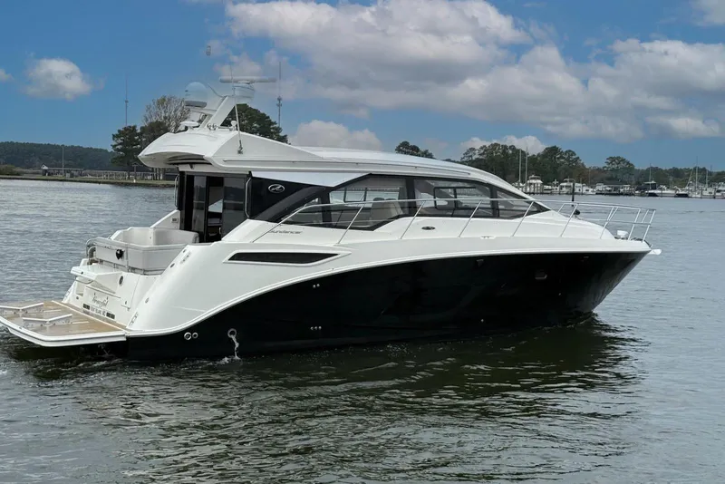 The Image of 2017 Sea Ray Sundancer 460 yacht cruising on a calm lake under a partly cloudy sky. - 0