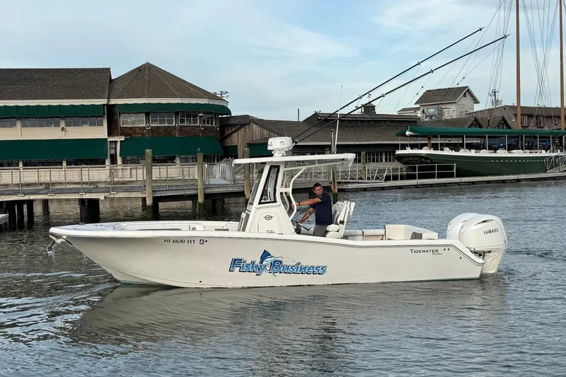 Slide: The Image of 2024 Tidewater 272 LXF boat named "Fishy Business" cruising near a marina. - 11