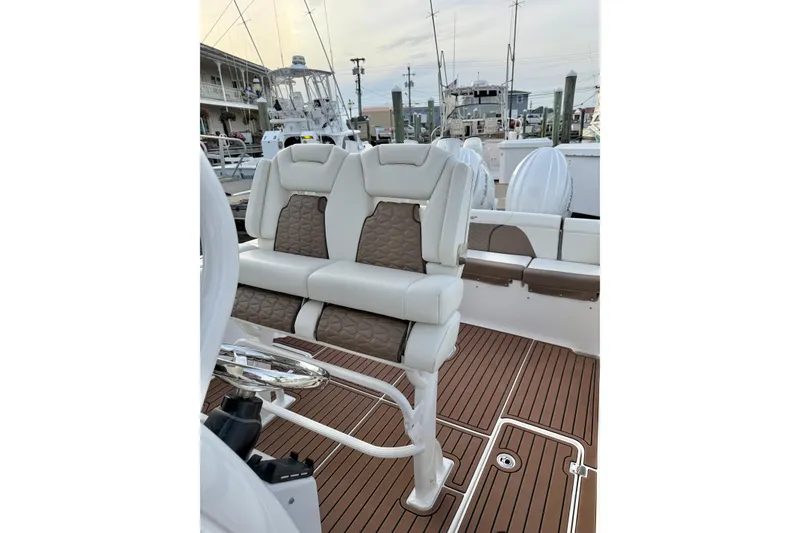 Slide: The Image of 2024 Tidewater 272 LXF boat interior with cushioned seating and wooden deck. - 15