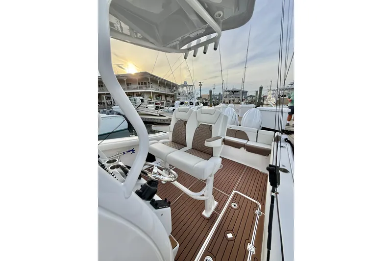 Slide: The Image of 2024 Tidewater 272 LXF boat interior with helm seats and teak flooring at marina. - 16