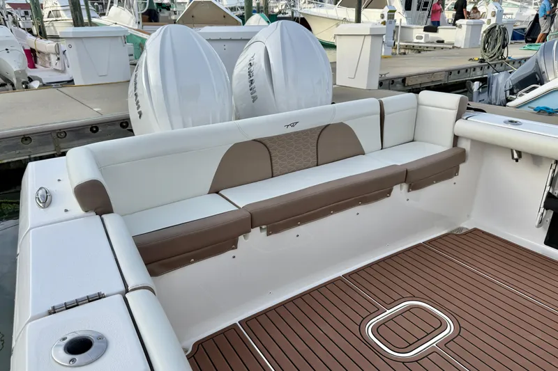 Slide: The Image of 2024 Tidewater 272 LXF boat with cushioned seating and twin Yamaha engines at dock. - 21