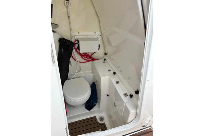 Slide: The Image of 2024 Tidewater 272 LXF boat interior with compact marine toilet and storage. - 25