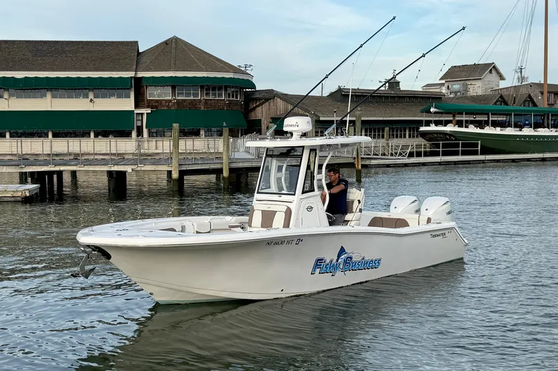 Slide: The Image of 2024 Tidewater 272 LXF boat cruising near a marina with fishing rods. - 9
